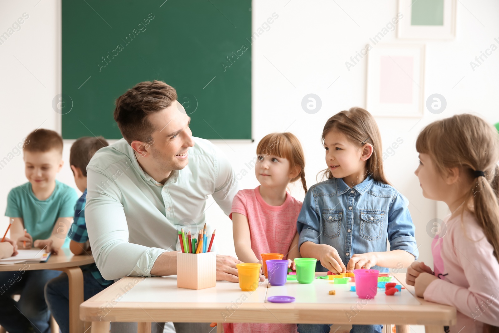 Photo of Cute little children with teacher in classroom at school