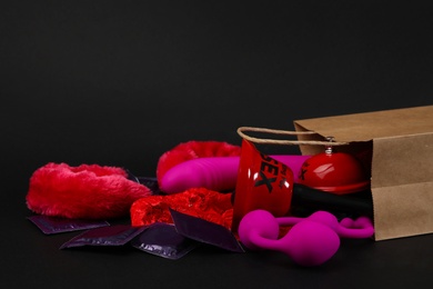 Photo of Shopping bag and different sex toys on black background