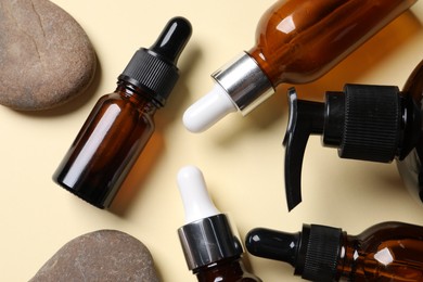 Face serums and other skin care products on beige background, flat lay