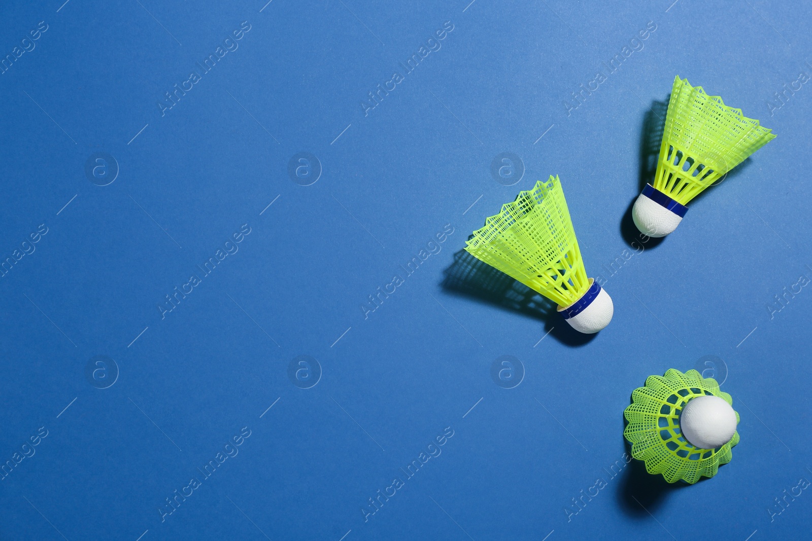 Photo of Badminton shuttlecocks on blue background, flat lay. Space for text
