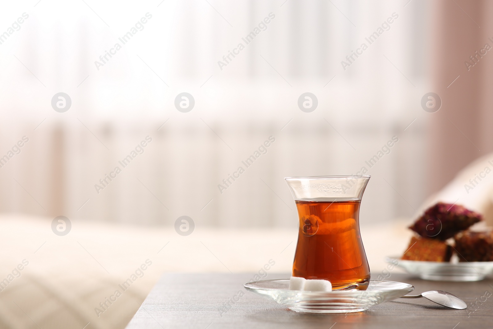 Photo of Glass with traditional Turkish tea and cookies on table indoors. Space for text