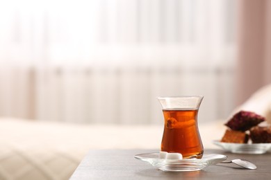 Photo of Glass with traditional Turkish tea and cookies on table indoors. Space for text