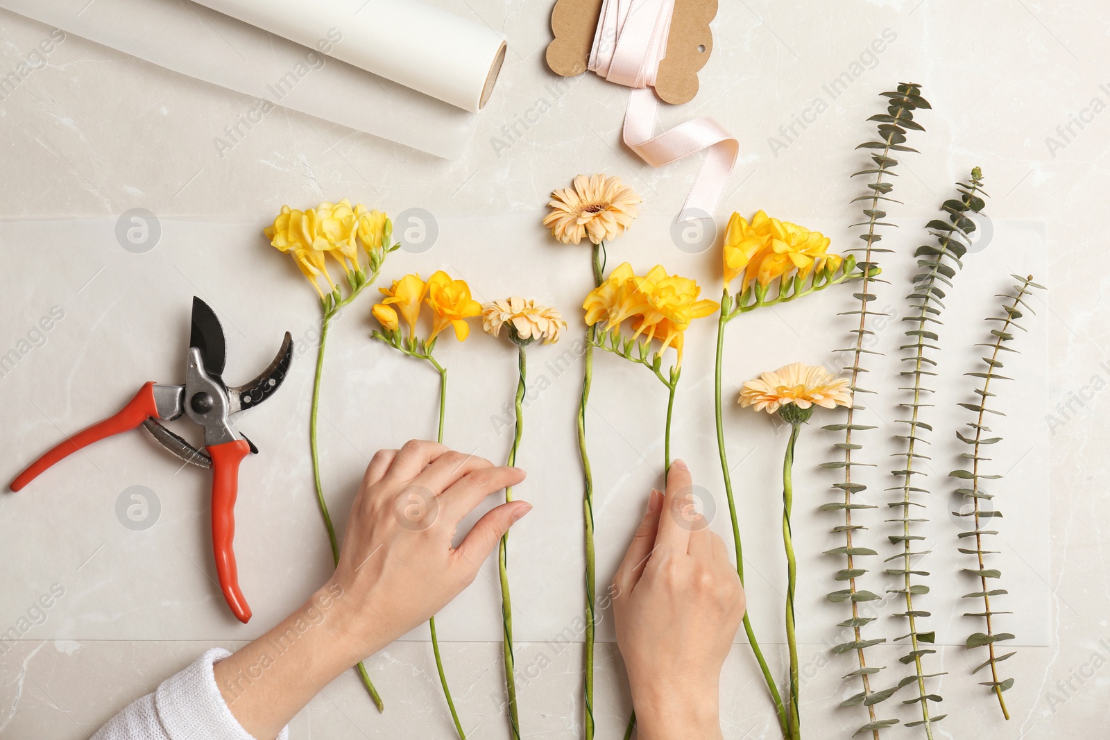 Photo of Female florist making beautiful bouquet at table, top view