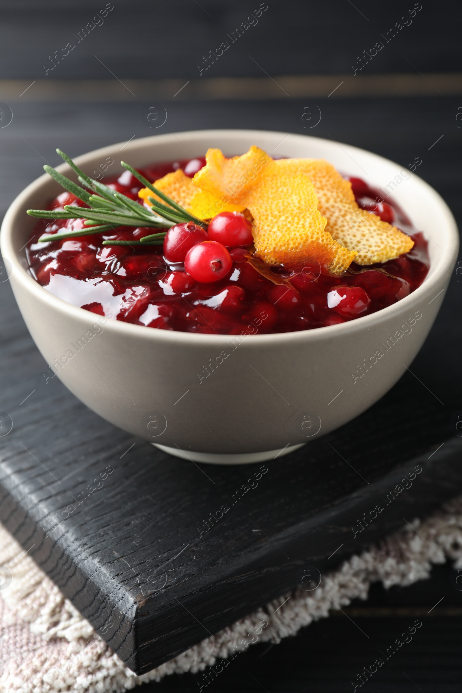 Photo of Fresh cranberry sauce, rosemary and orange peel in bowl on table, closeup