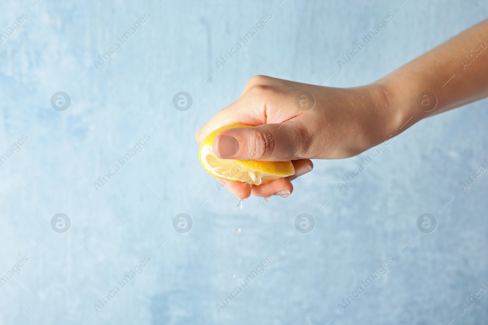 Photo of Young woman squeezing lemon on color background