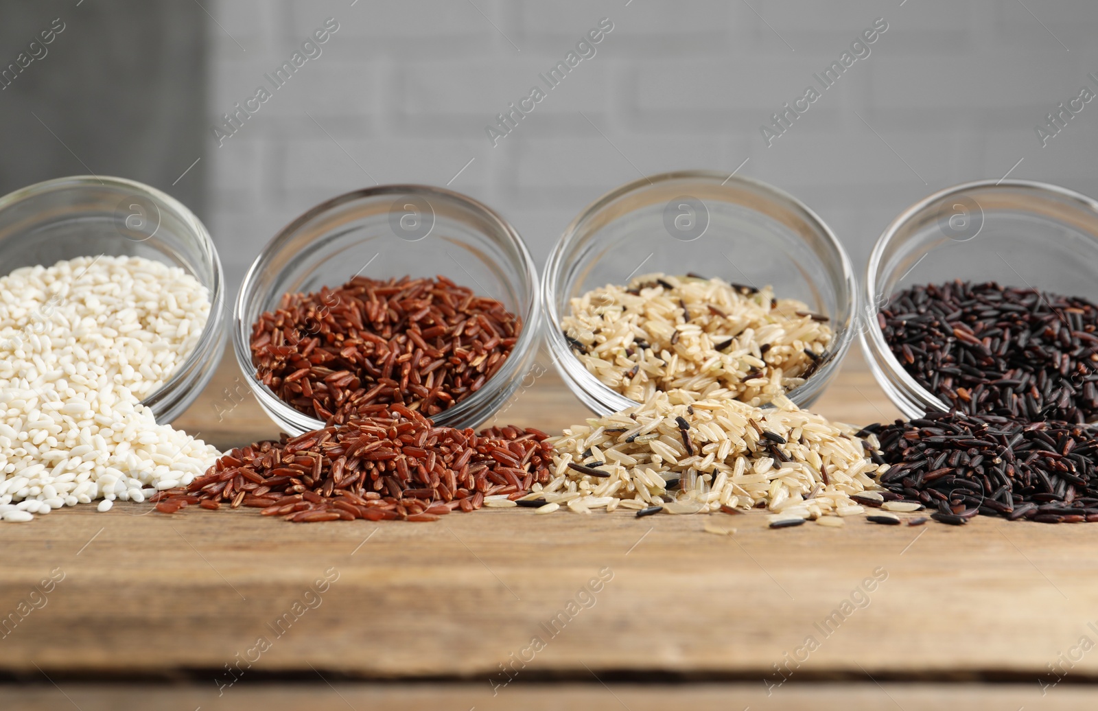 Photo of Different types of rice on wooden table, closeup