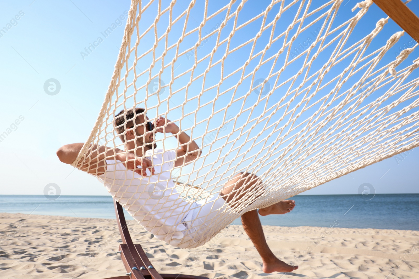 Photo of Young man relaxing in hammock on beach