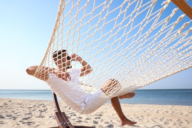 Young man relaxing in hammock on beach