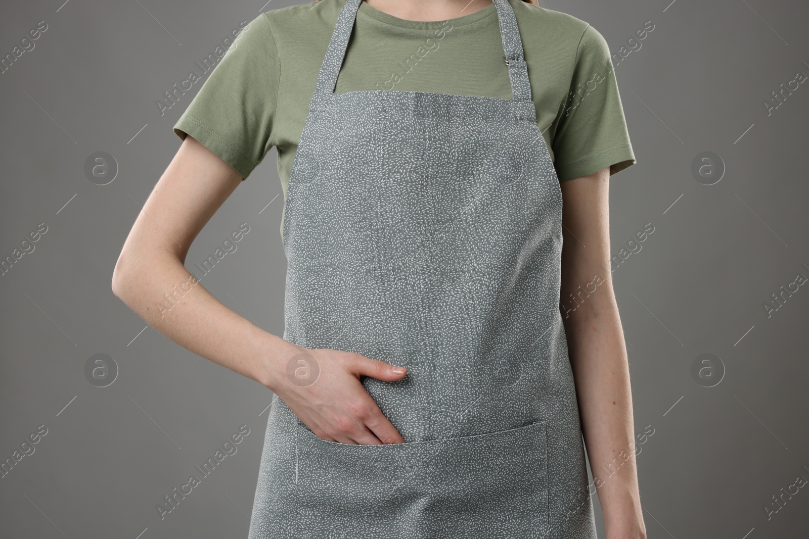 Photo of Woman wearing kitchen apron on grey background, closeup. Mockup for design