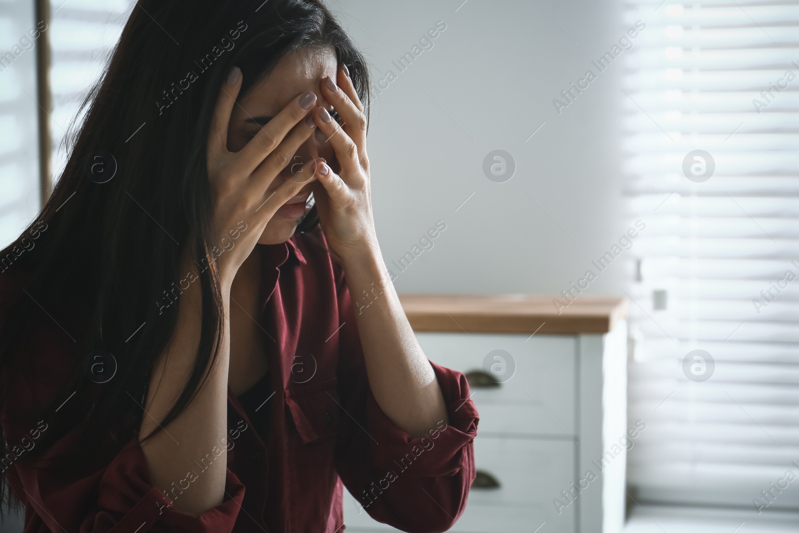 Photo of Abused young woman crying indoors, space for text. Domestic violence concept