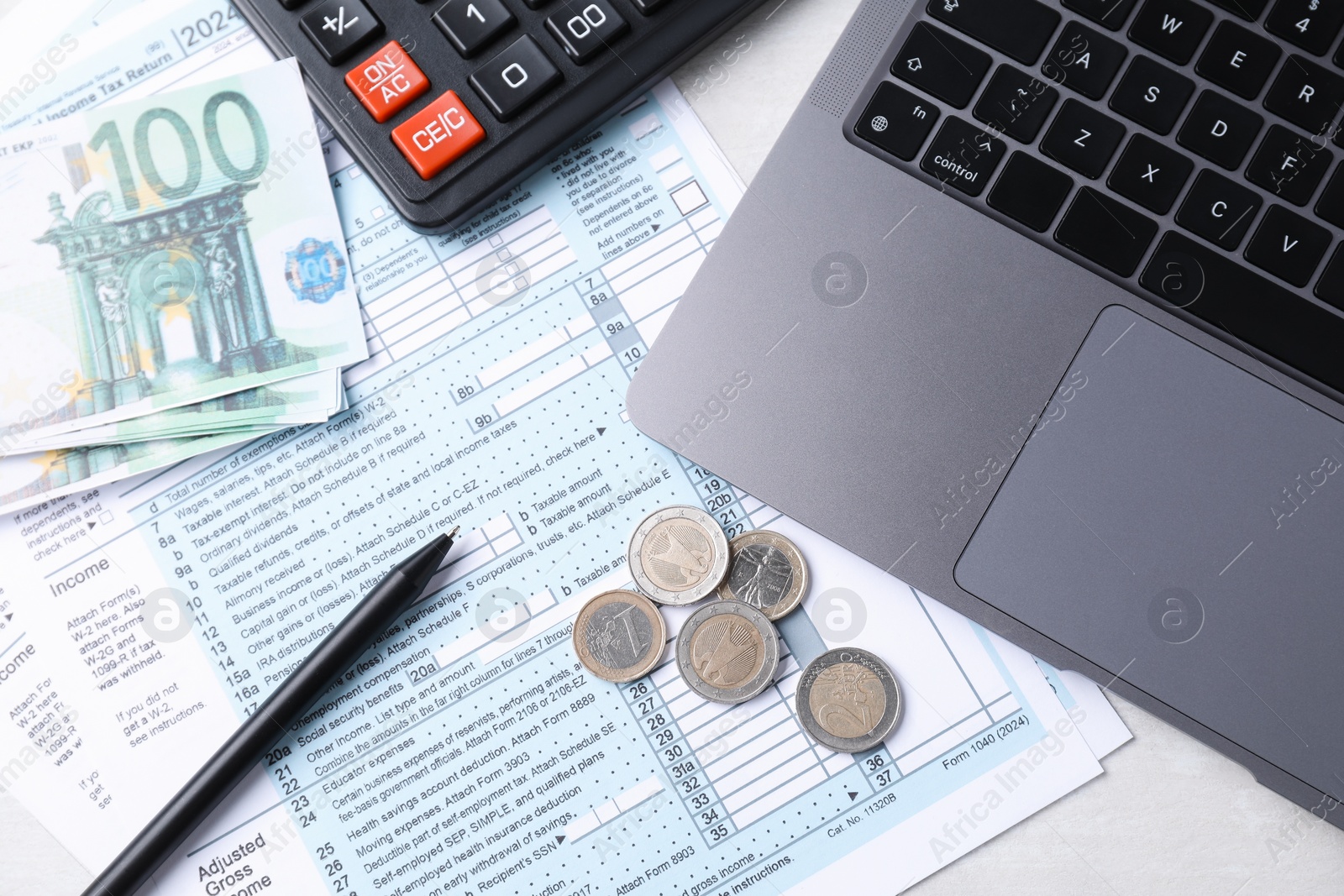 Photo of Tax forms, money, pen, calculator and laptop on light grey table, top view