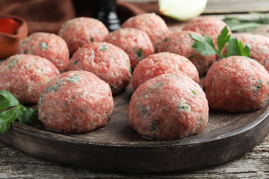 Photo of Many fresh raw meatballs on wooden table, closeup