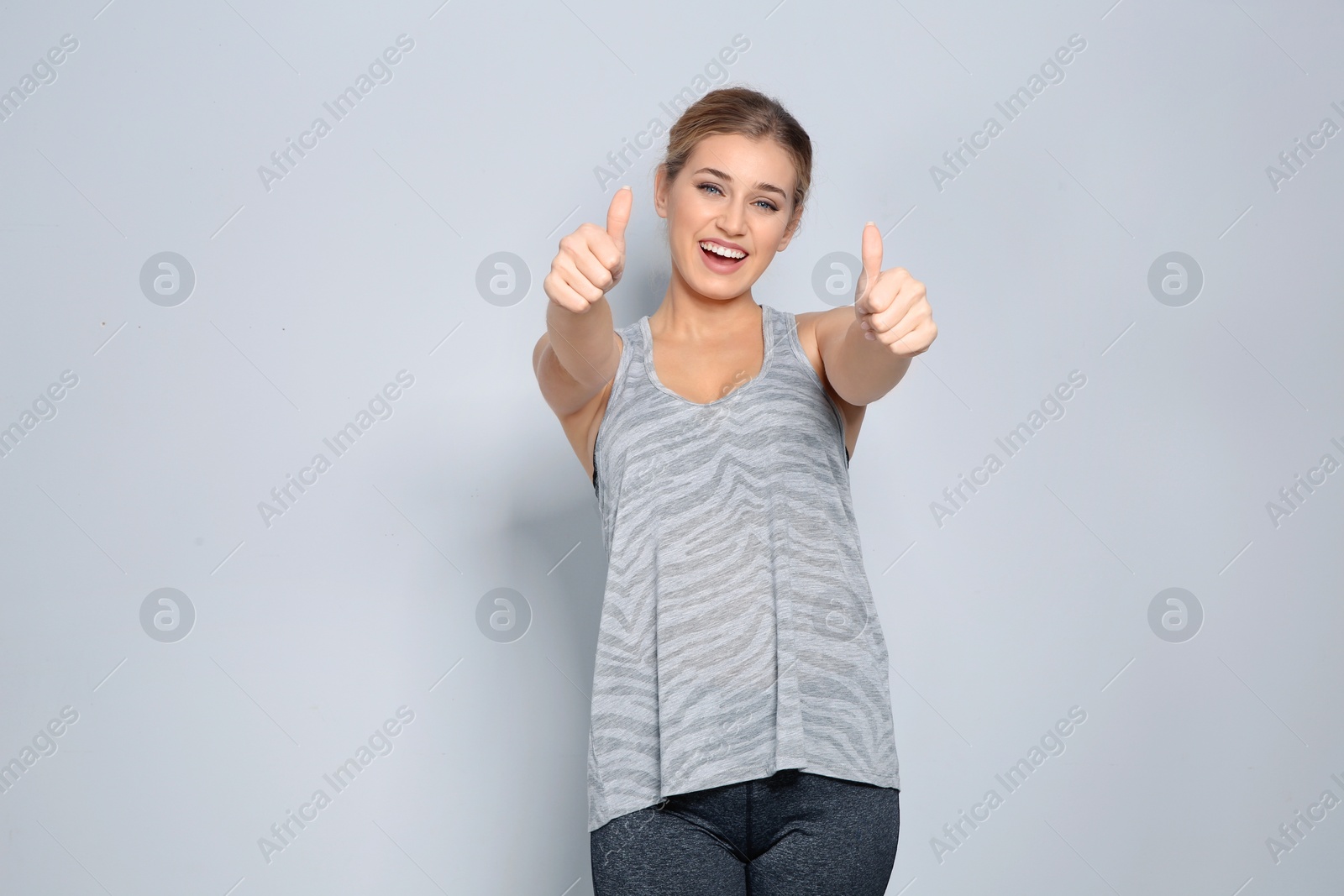 Photo of Happy young woman showing thumbs up on color background. Celebrating victory