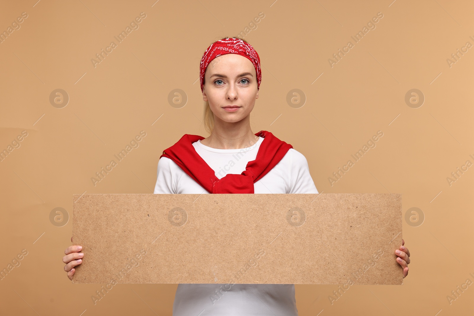 Photo of Beautiful woman holding blank cardboard banner on beige background, space for text