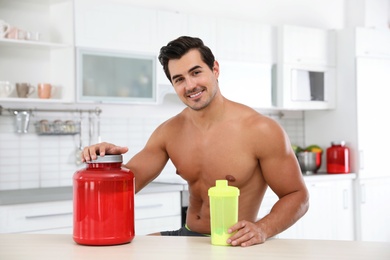 Young shirtless athletic man with protein shake powder in kitchen