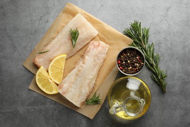 Photo of Fresh raw cod fillets, spices and lemon slices on grey table, flat lay