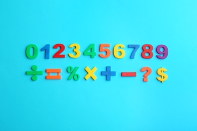 Photo of Colorful magnetic numbers and math symbols on light blue background, flat lay