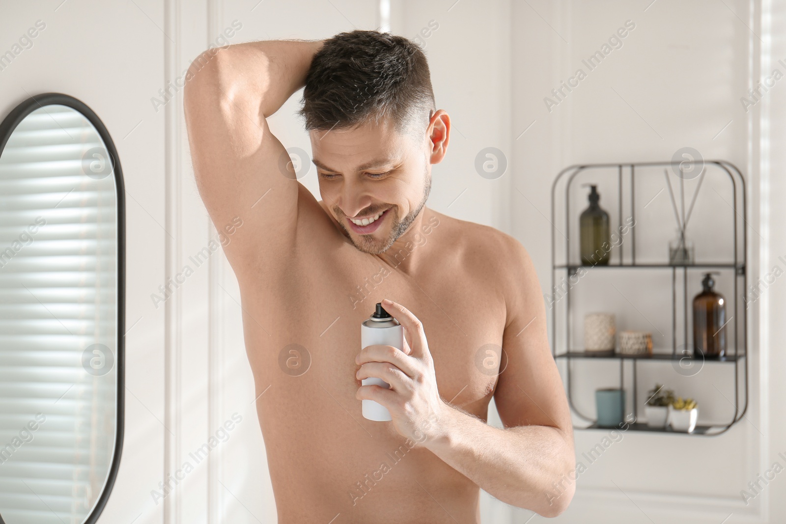 Photo of Handsome man applying deodorant in bathroom at home