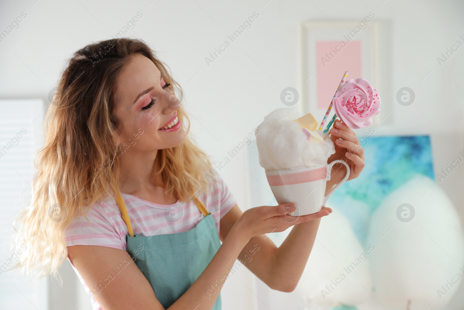 Photo of Young woman with cup of cotton candy dessert indoors