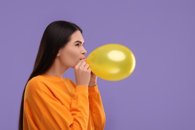 Photo of Woman inflating yellow balloon on purple background, space for text