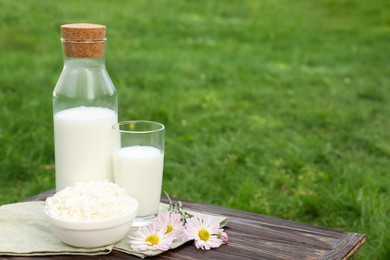 Photo of Tasty fresh milk and cottage cheese on wooden table outdoors. Space for text