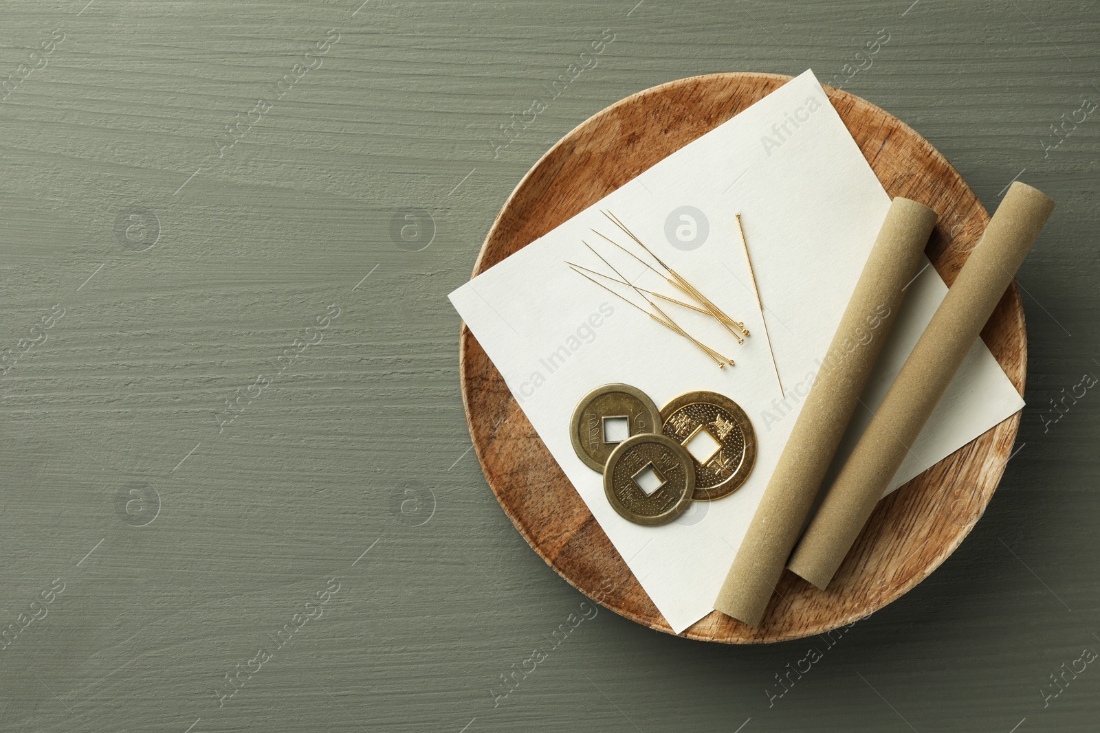 Photo of Acupuncture needles, moxa sticks and antique Chinese coins on grey wooden table, top view. Space for text