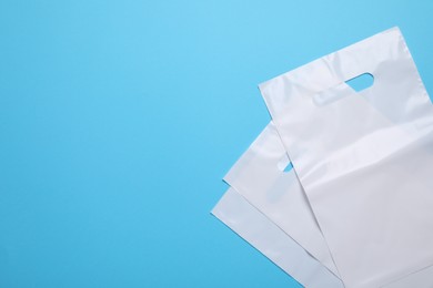 Photo of White plastic bags on light blue background, top view. Space for text