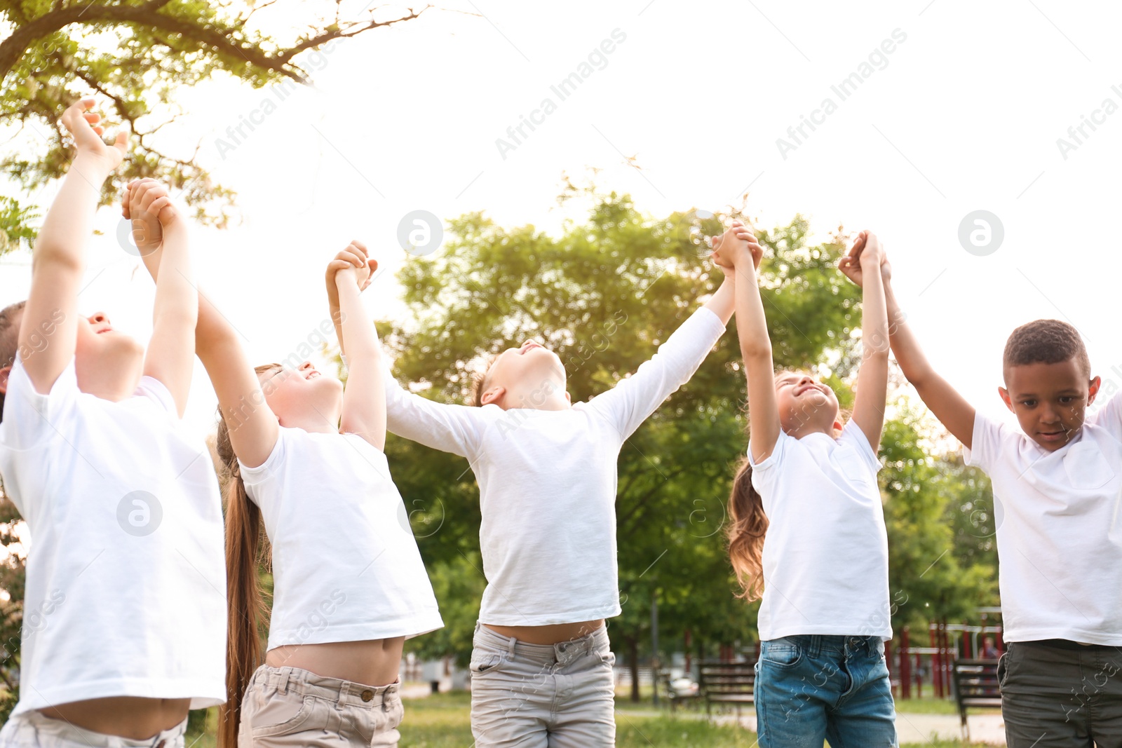 Photo of Group of children holding hands up in park. Volunteer project