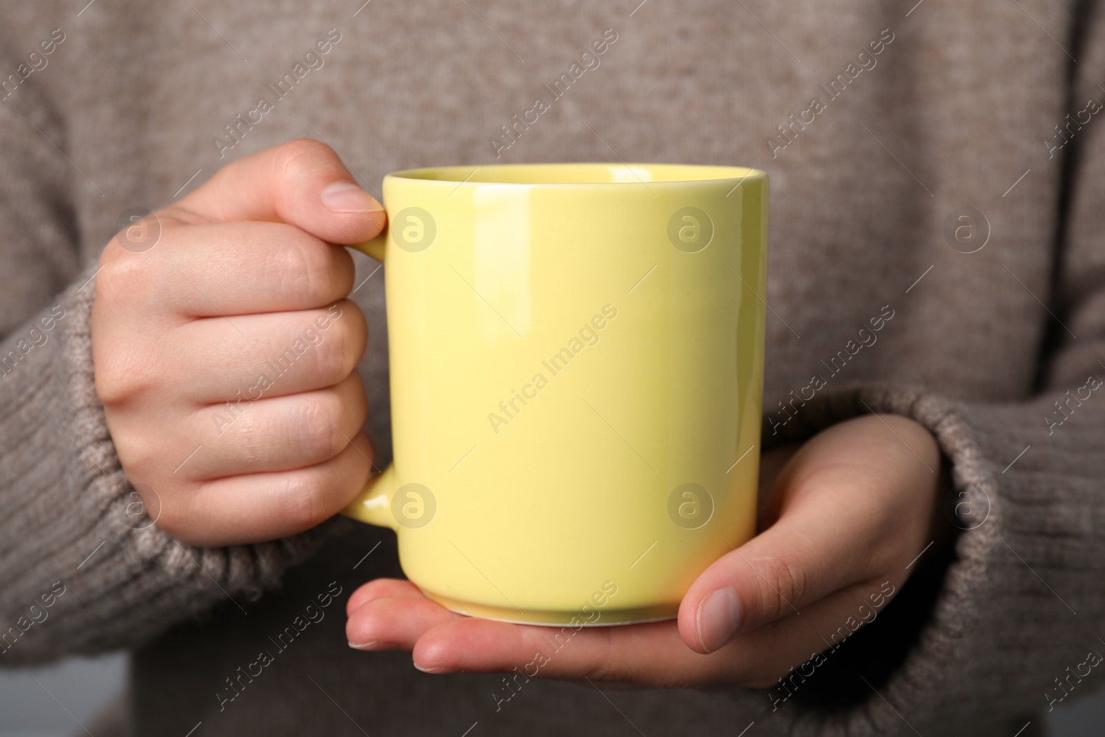 Photo of Woman holding yellow mug, closeup. Mockup for design