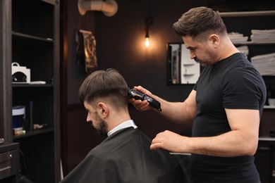 Photo of Professional hairdresser making stylish haircut in barbershop
