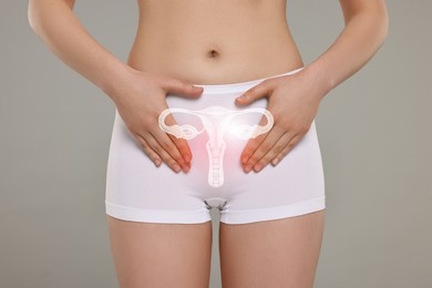 Woman in underwear and illustration of reproductive system on light grey background, closeup