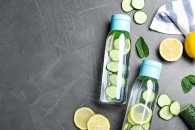 Photo of Bottles of refreshing water with cucumber, lemon and mint on black table, flat lay. Space for text