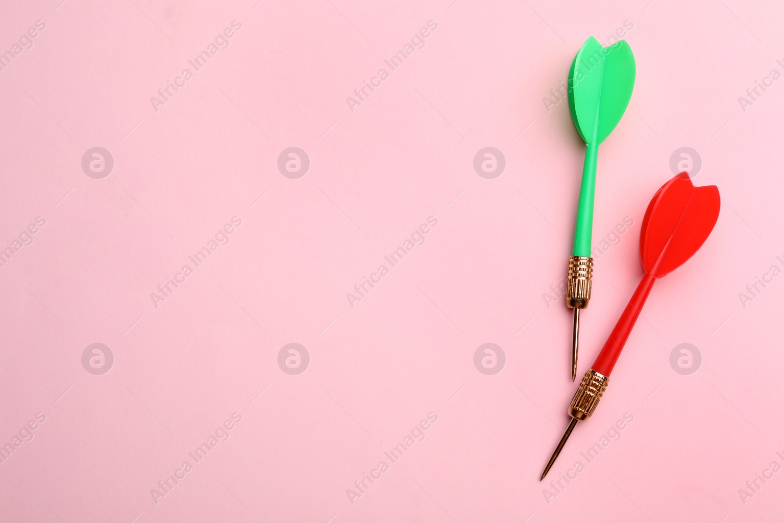 Photo of Plastic dart arrows on pink background, flat lay with space for text