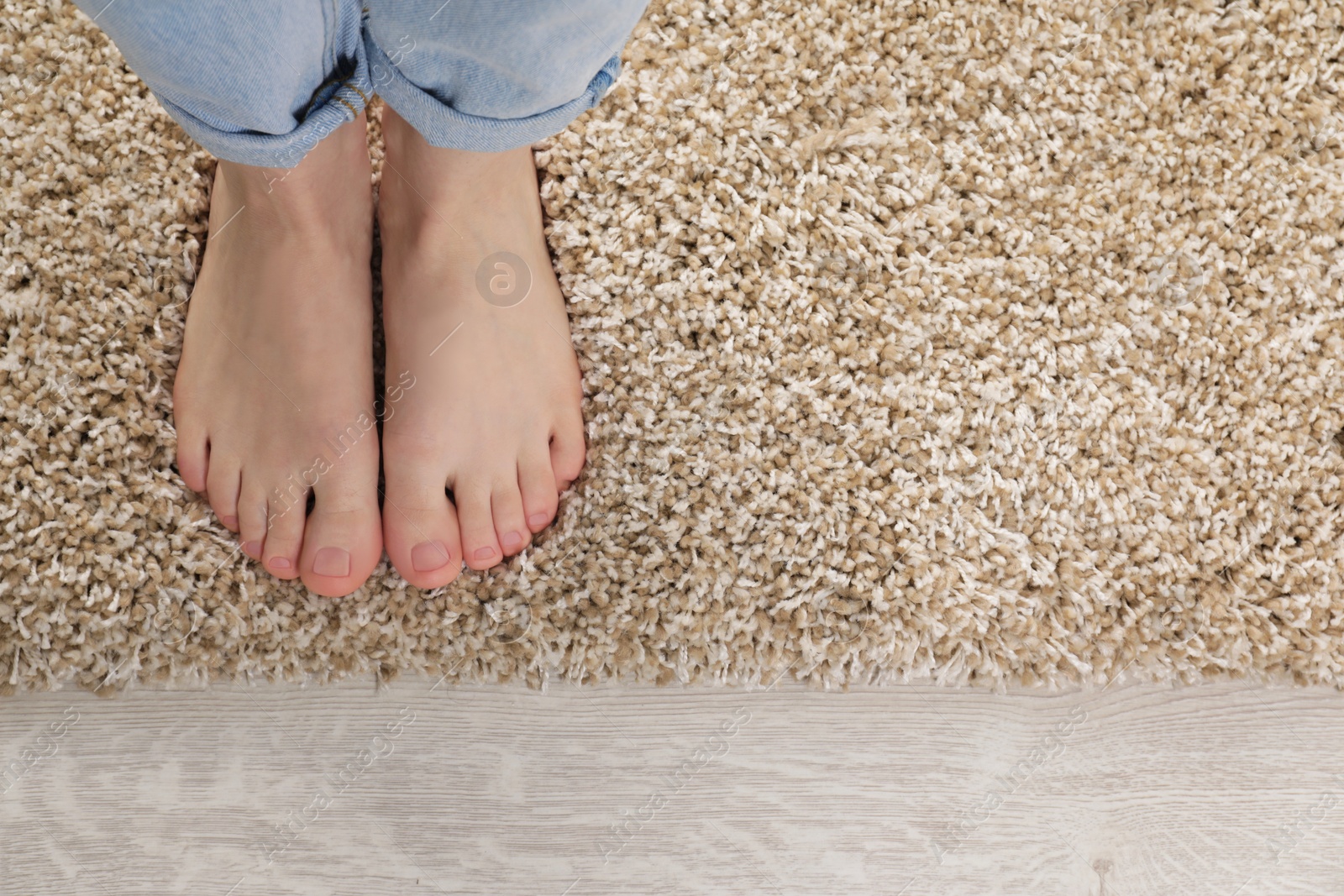 Photo of Woman standing on soft carpet at home, top view