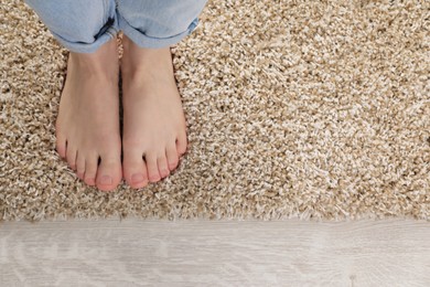 Woman standing on soft carpet at home, top view