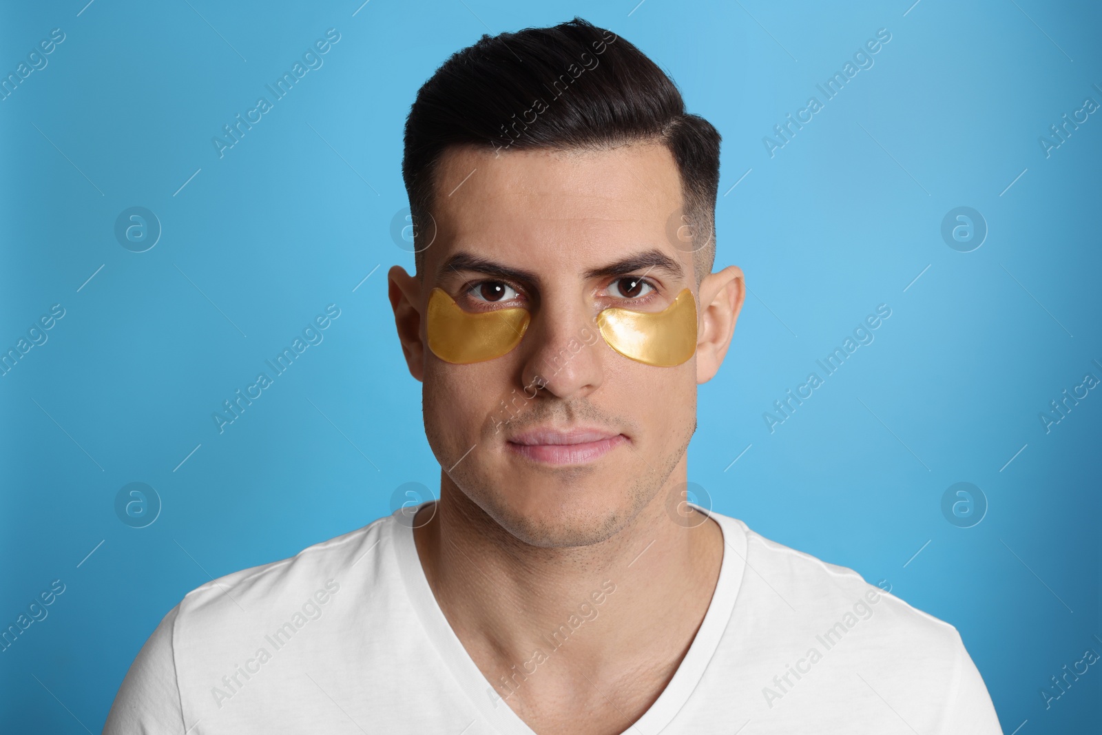 Photo of Man with golden under eye patches on light blue background