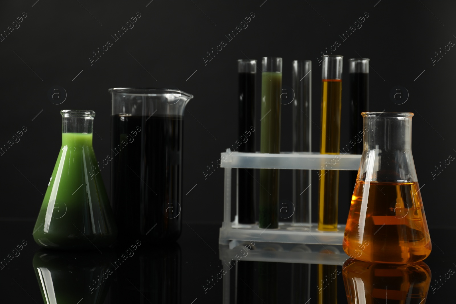 Photo of Laboratory glassware with different types of oil on black background