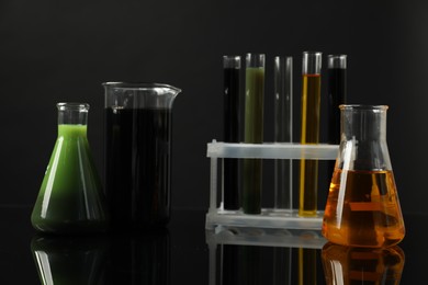 Laboratory glassware with different types of oil on black background