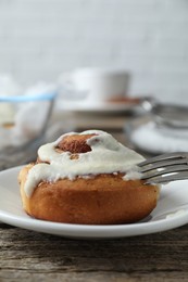 Photo of Tasty cinnamon roll with cream on wooden table, closeup. Space for text