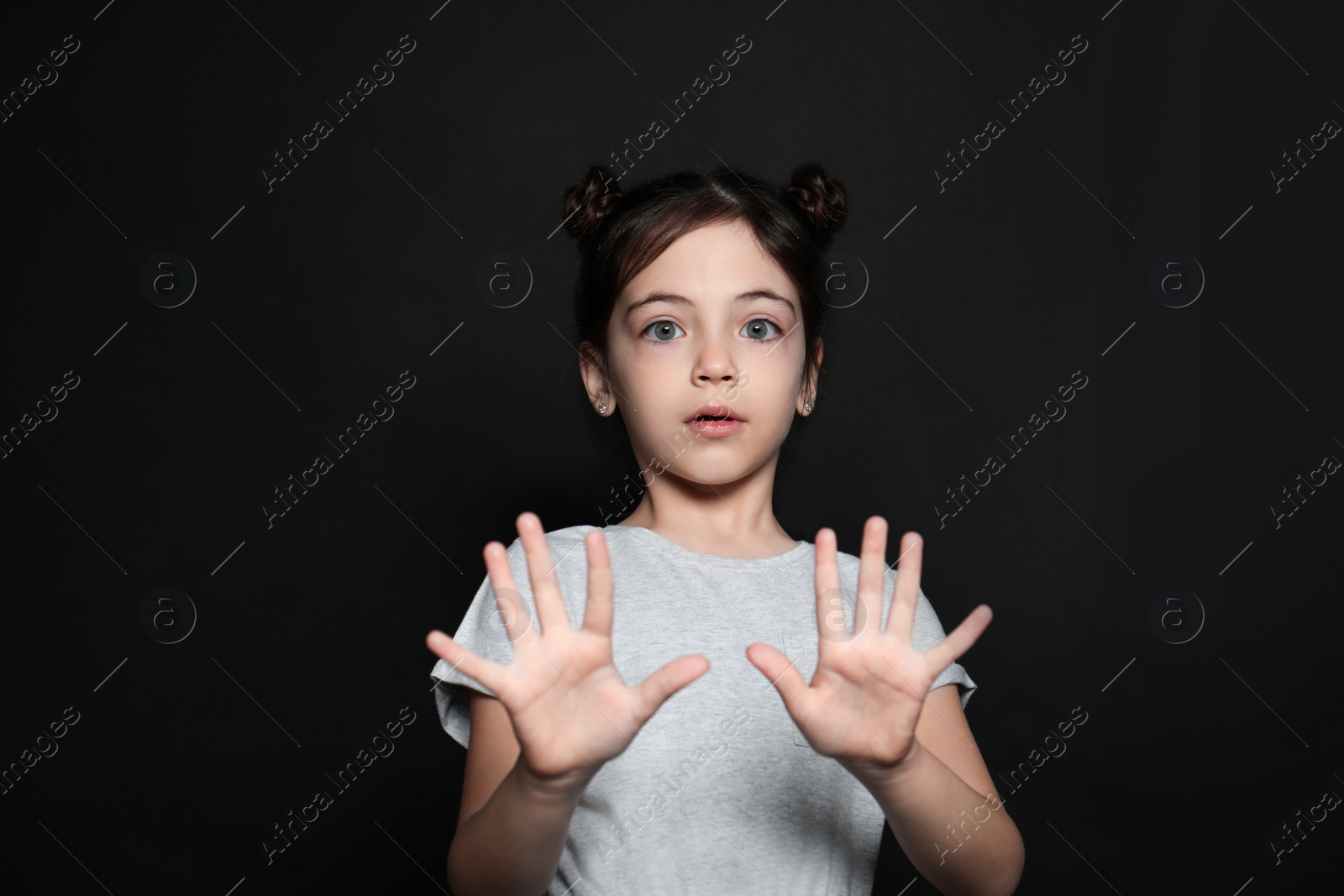 Photo of Little girl feeling fear on black background