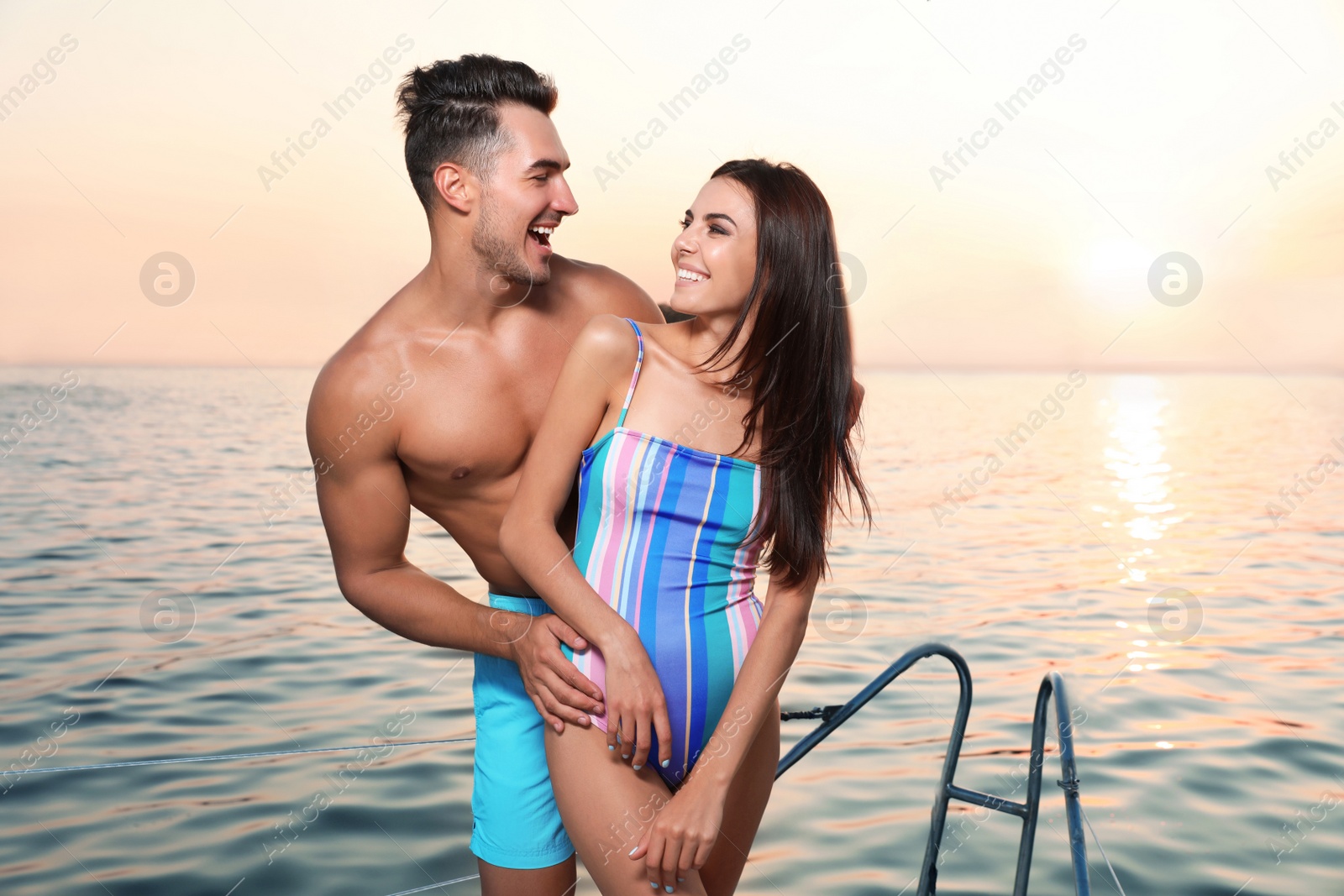 Photo of Young man and his beautiful girlfriend in bikini on yacht. Happy couple during sea trip