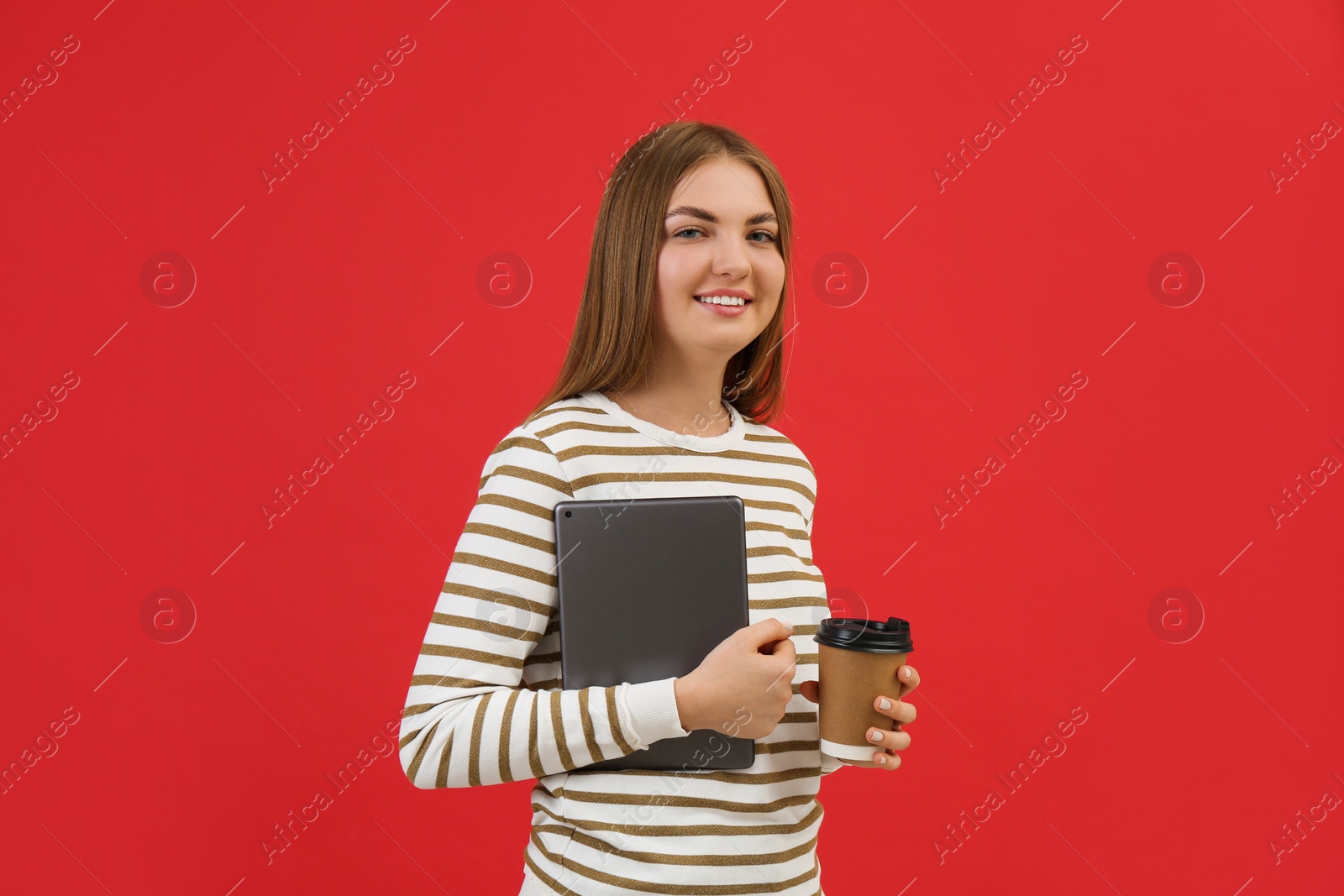 Photo of Teenage student with tablet and paper cup of coffee on red background