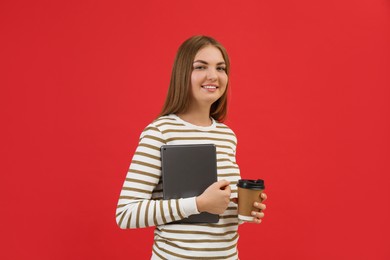 Teenage student with tablet and paper cup of coffee on red background
