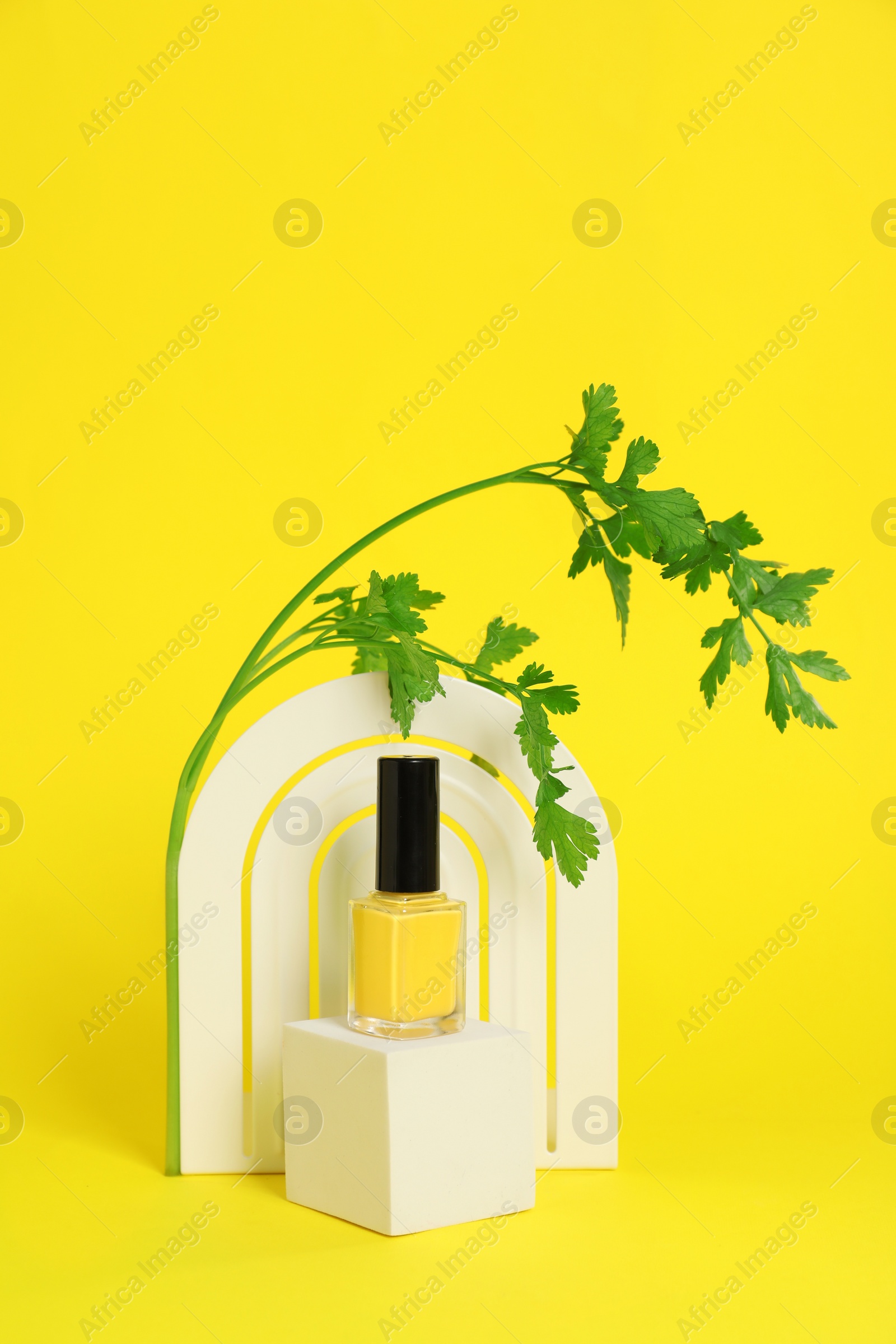 Photo of Stylish presentation of beautiful nail polish in bottle on yellow background