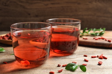 Photo of Healthy goji juice in glasses on wooden table