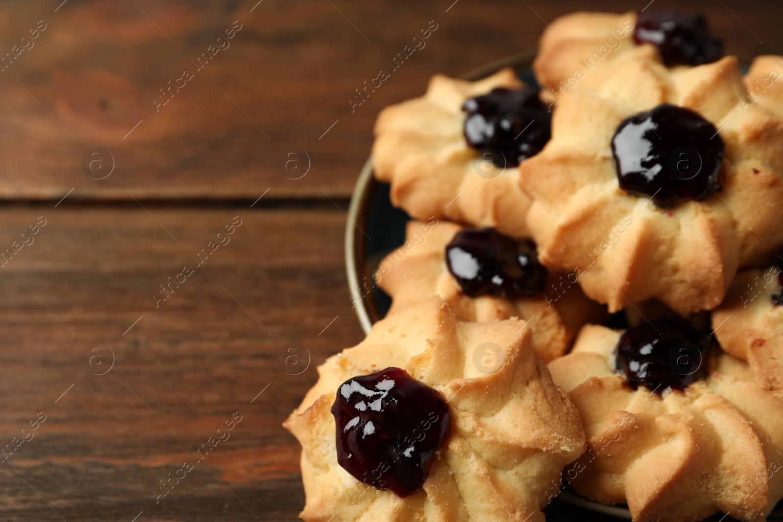 Photo of Tasty shortbread cookies with jam on wooden table, closeup. Space for text