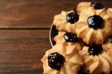 Tasty shortbread cookies with jam on wooden table, closeup. Space for text