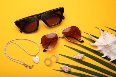 Flat lay composition with stylish sunglasses, seashells and accessories on yellow background