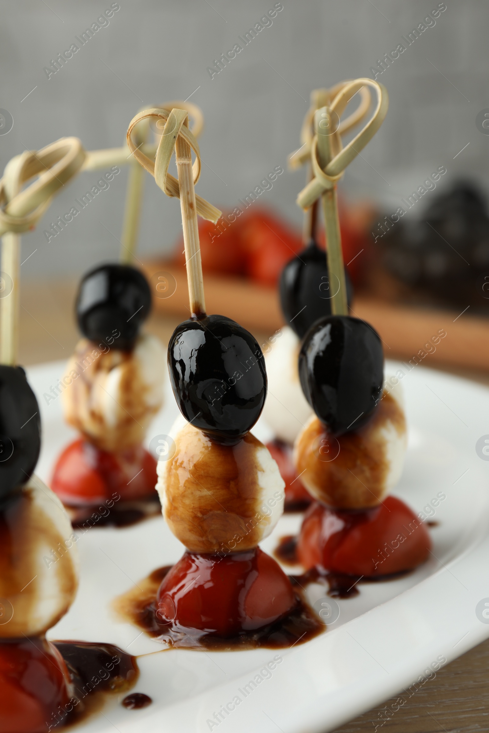 Photo of Tasty canapes with black olives, mozzarella and cherry tomatoes on table, closeup