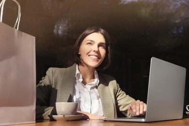 Special Promotion. Happy young woman using laptop at table in cafe